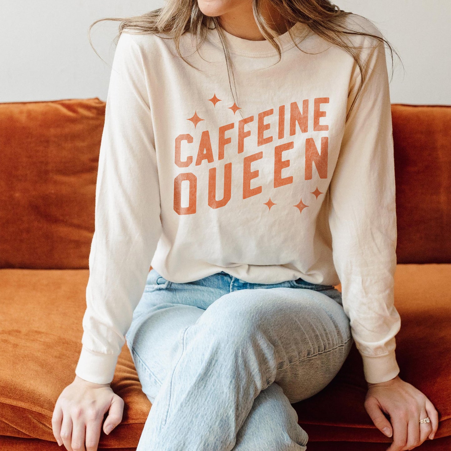 
                  
                    a young woman wearing a long sleeved, caffeine queen tee in Ivory
                  
                