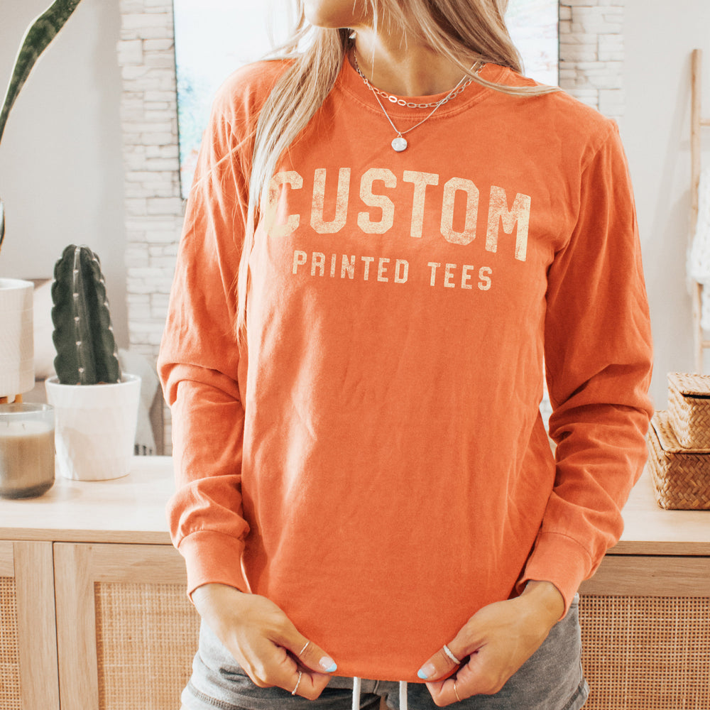 a young woman wearing a long sleeve, comfort colors, custom printed tee in Melon