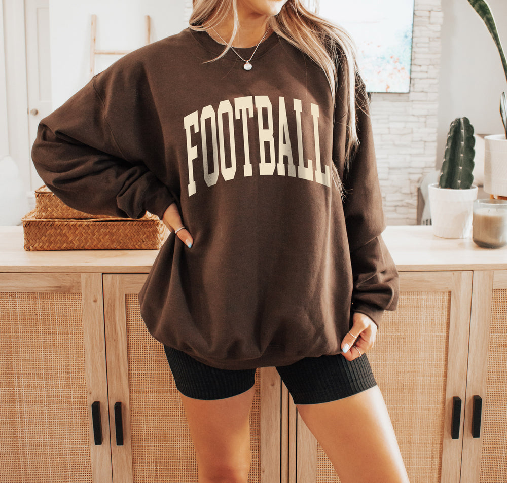 a young woman wearing an oversized football sweatshirt in Dark Chocolate