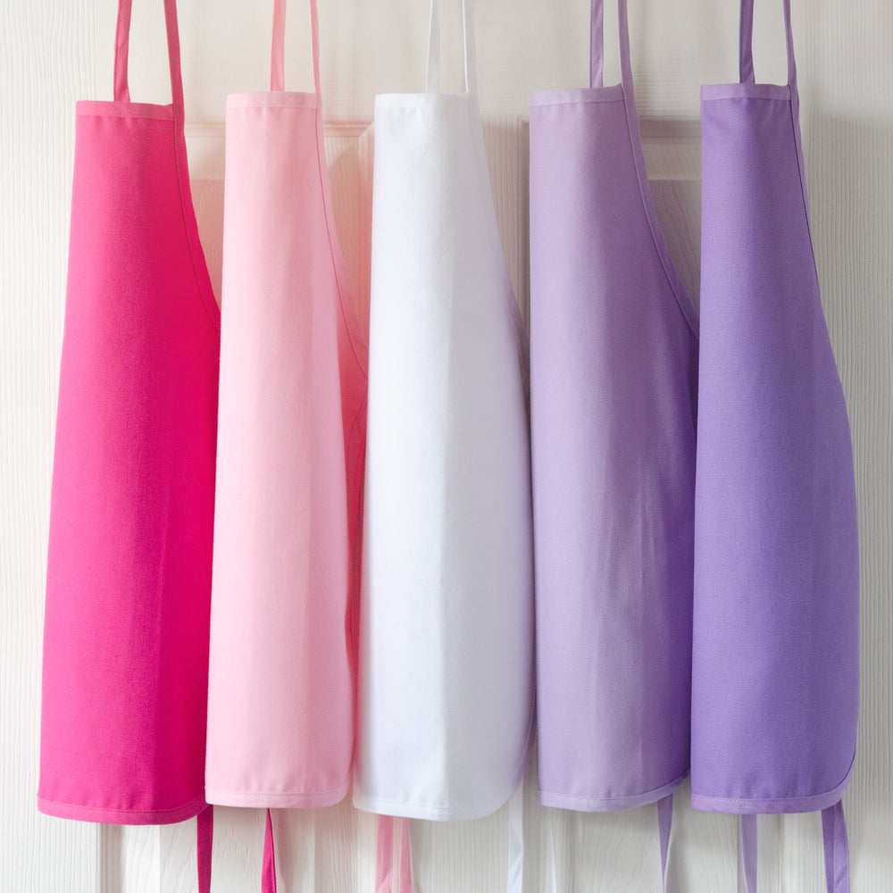 Toddler Cotton Aprons in multiple colors hung on a door