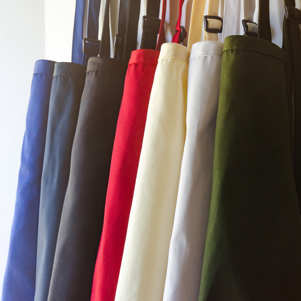 a sun washed row of hanging aprons in multiple colors