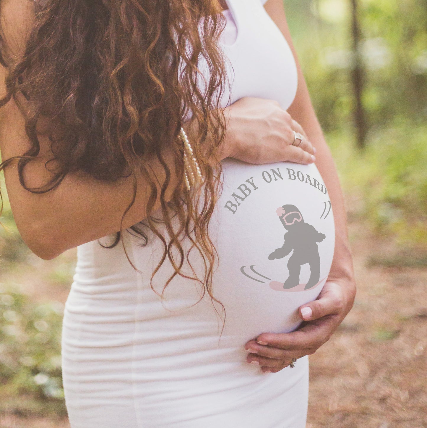 
                  
                    A pregnant woman in a white dress with Baby on Board - Snowboarding Girl svg printed on the belly, as a gender reveal
                  
                