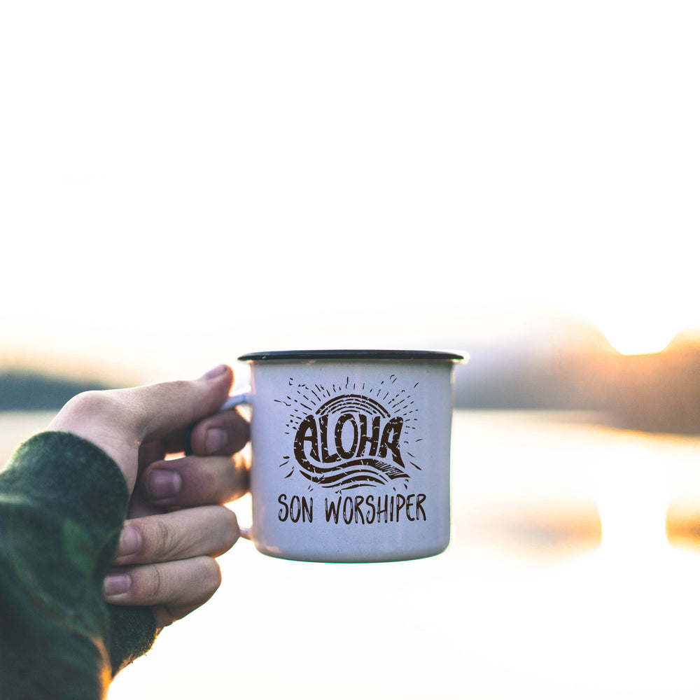 
                  
                    aloha son worshiper svg shown on a mug held in front of a morning lake scene
                  
                