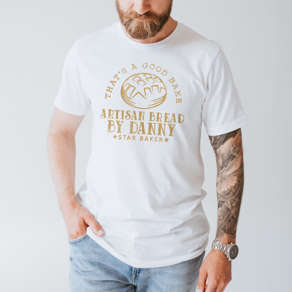 a handsome tattooed and bearded young  man wearing a personalized sourdough baking shirt in white
