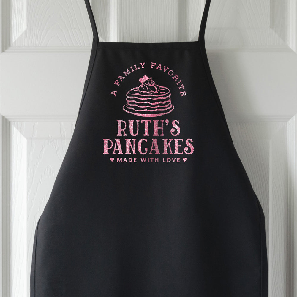 a personalized pancake apron for kids shown in black with flamingo pink glitter print