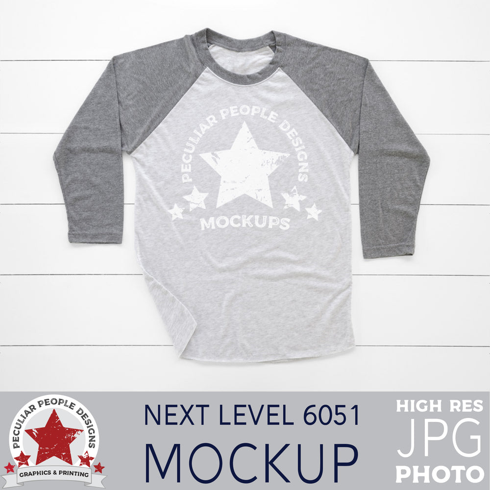 mock up photo of a grey raglan, layed out in a masculine way, on a wood background