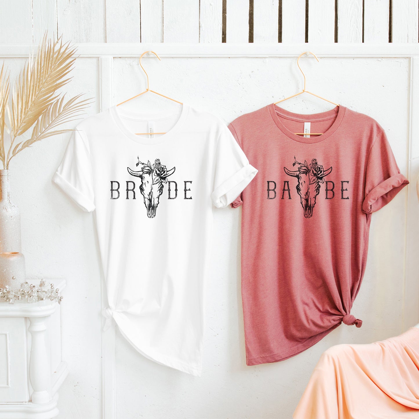 
                  
                    bride and babe bachelorette shirts hanging in a feminine decorated room
                  
                