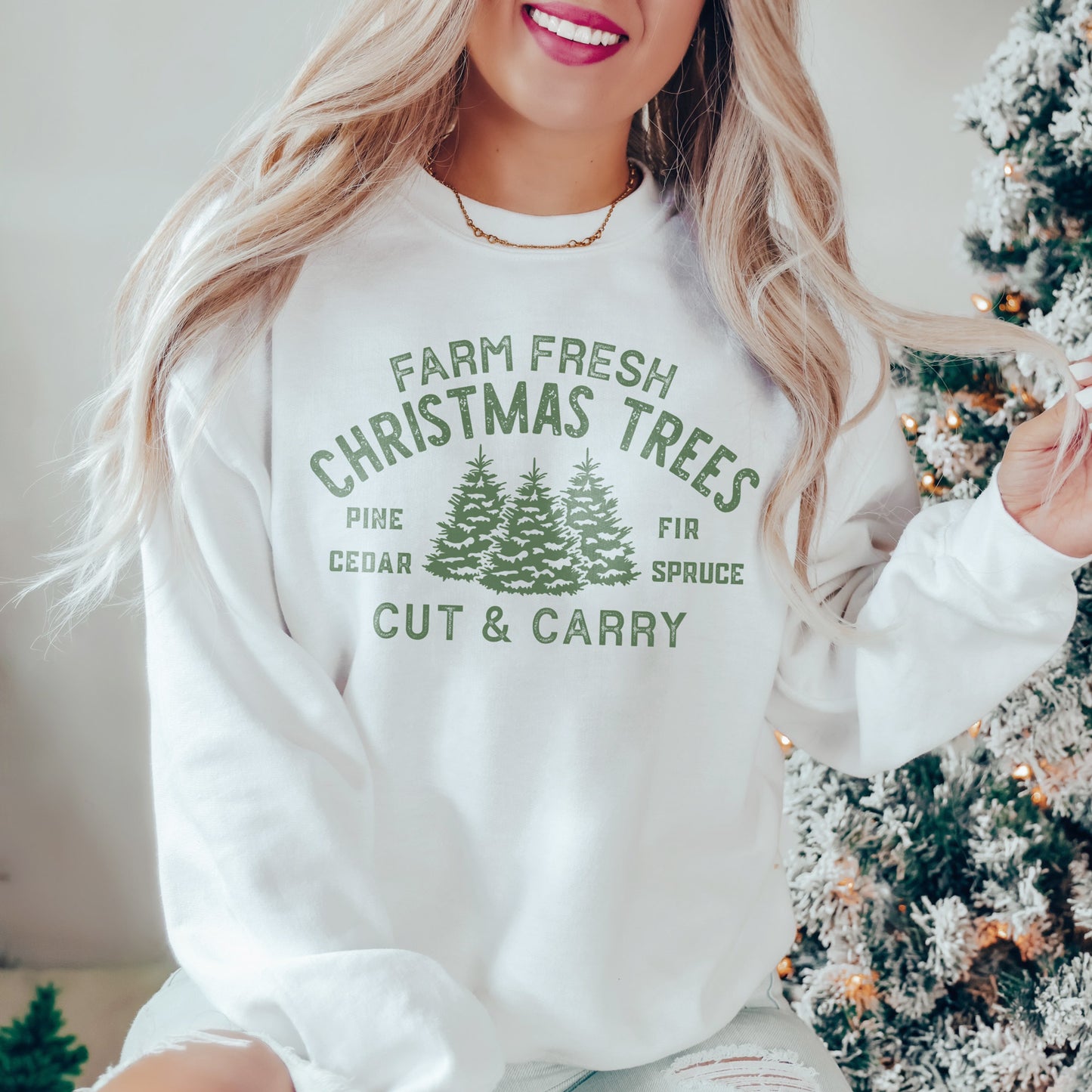 a young woman wearing a farm fresh christmas trees sweatshirt in white