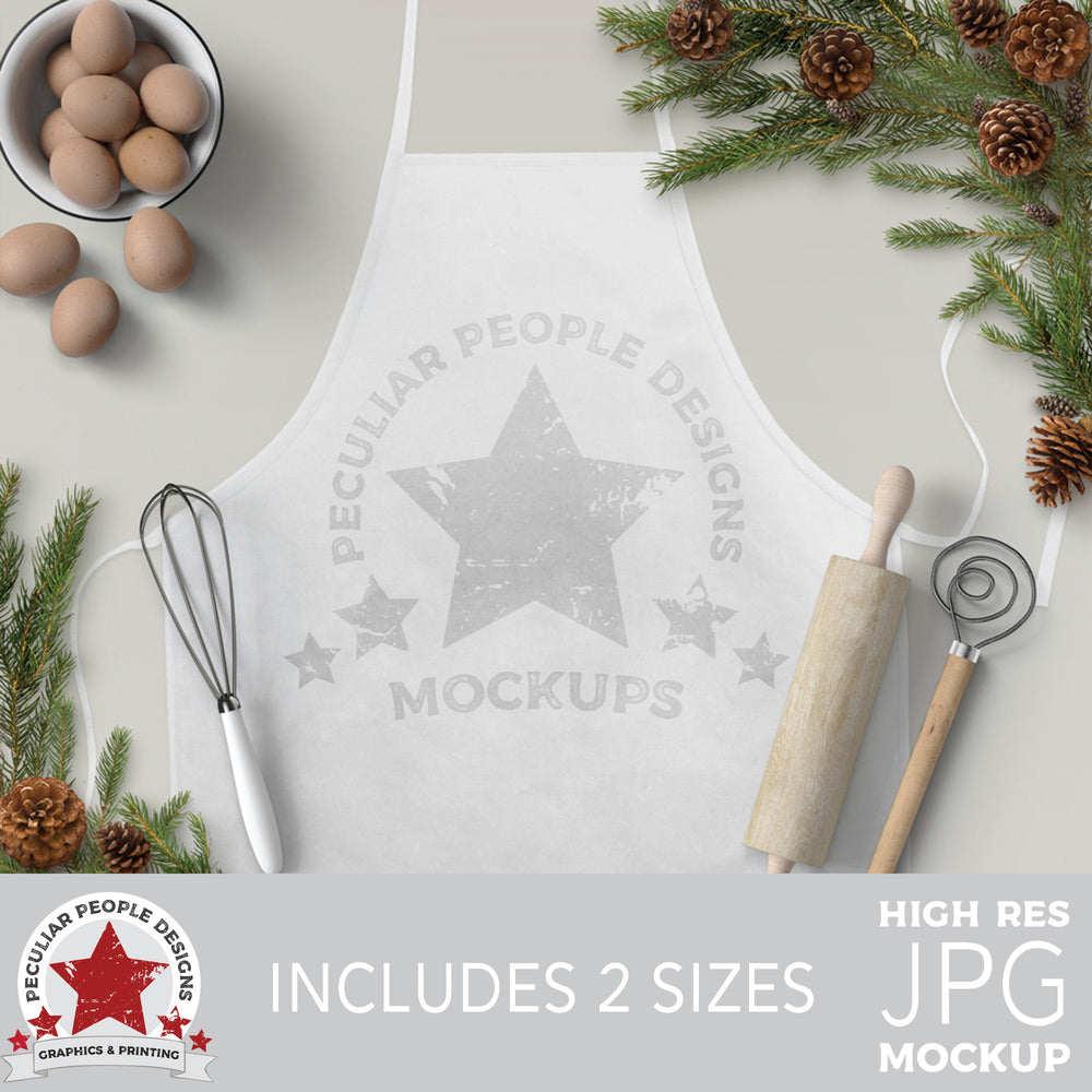 a mockup image with farmhouse charm. Pine cones and branches, a bowl of eggs, and baking utensils surround a white apron