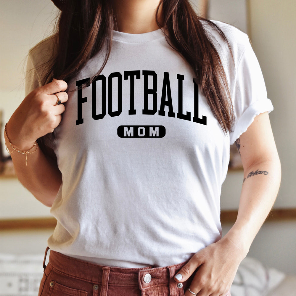 
                  
                    a young woman wearing  a football mom shirt in white
                  
                