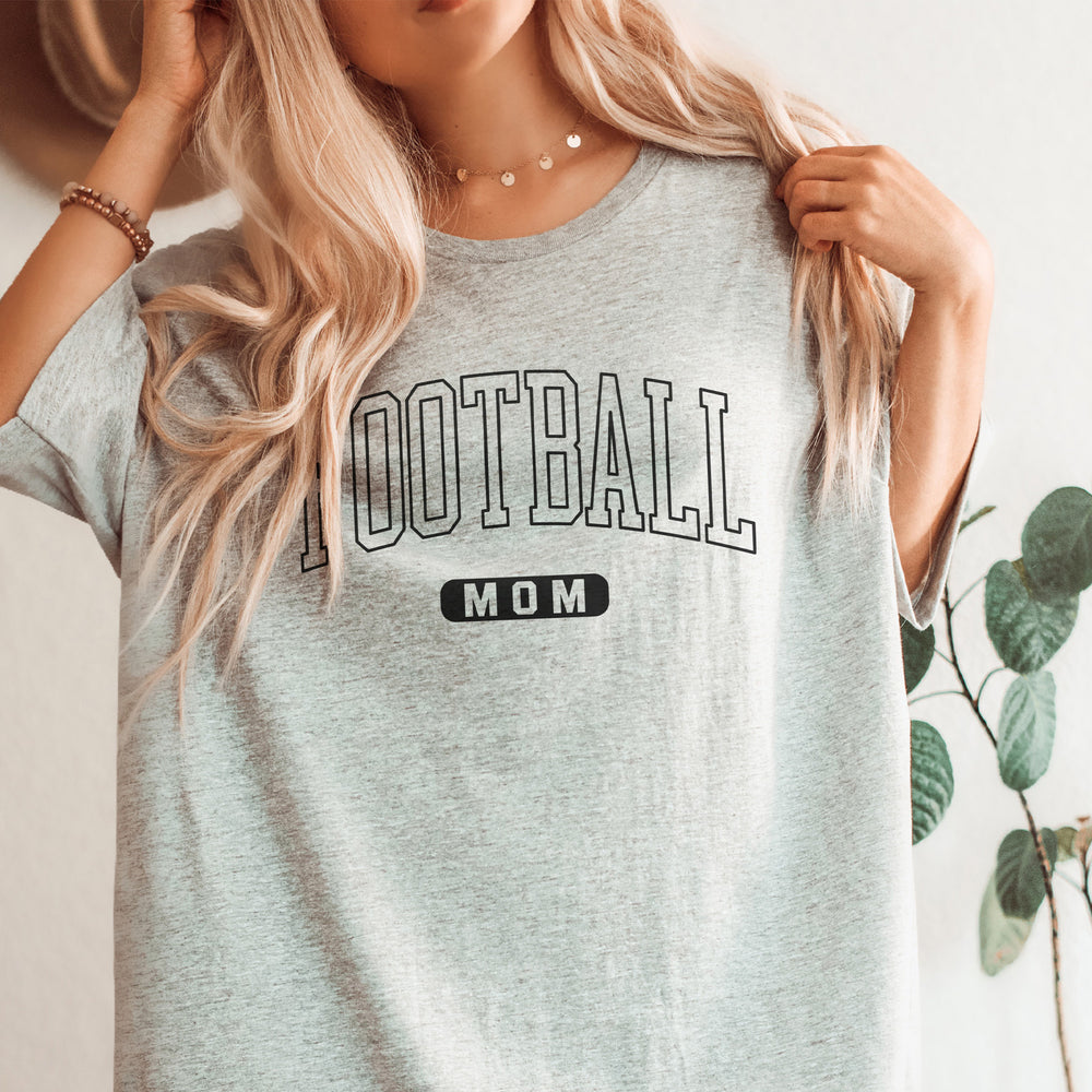 
                  
                    a young woman wearing an oversized football mom shirt in grey
                  
                