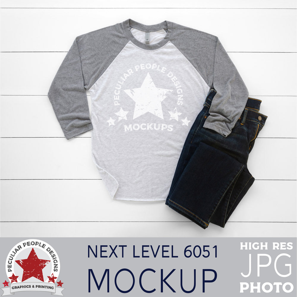 mock up photo of a grey raglan, layed out in a masculine way with men's jeans, on a wood background