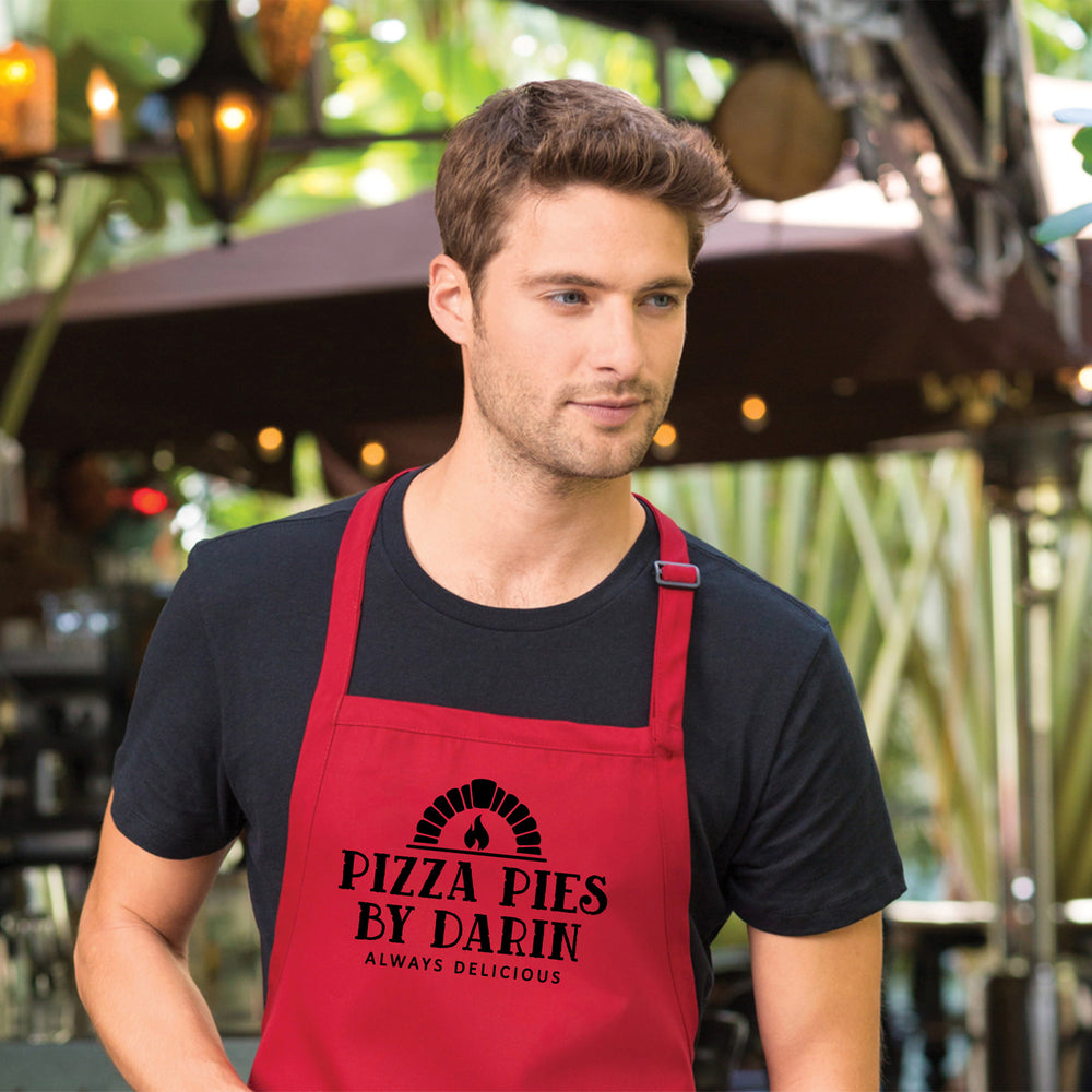 a young man outdoors, wearing a personalized pizza oven apron in red