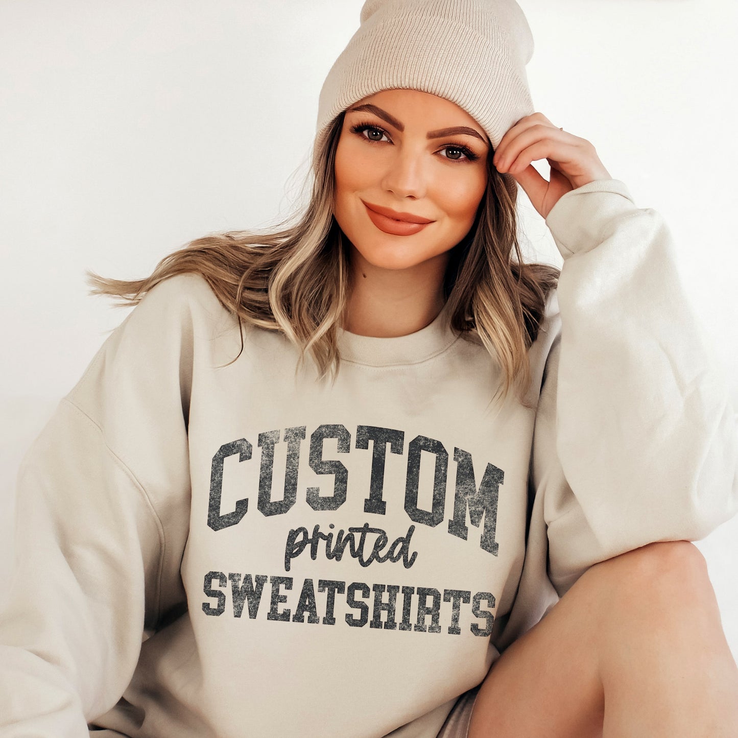 
                  
                    a pretty woman wearing a sand sweatshirt with text that reads "design your own sweatshirt"
                  
                