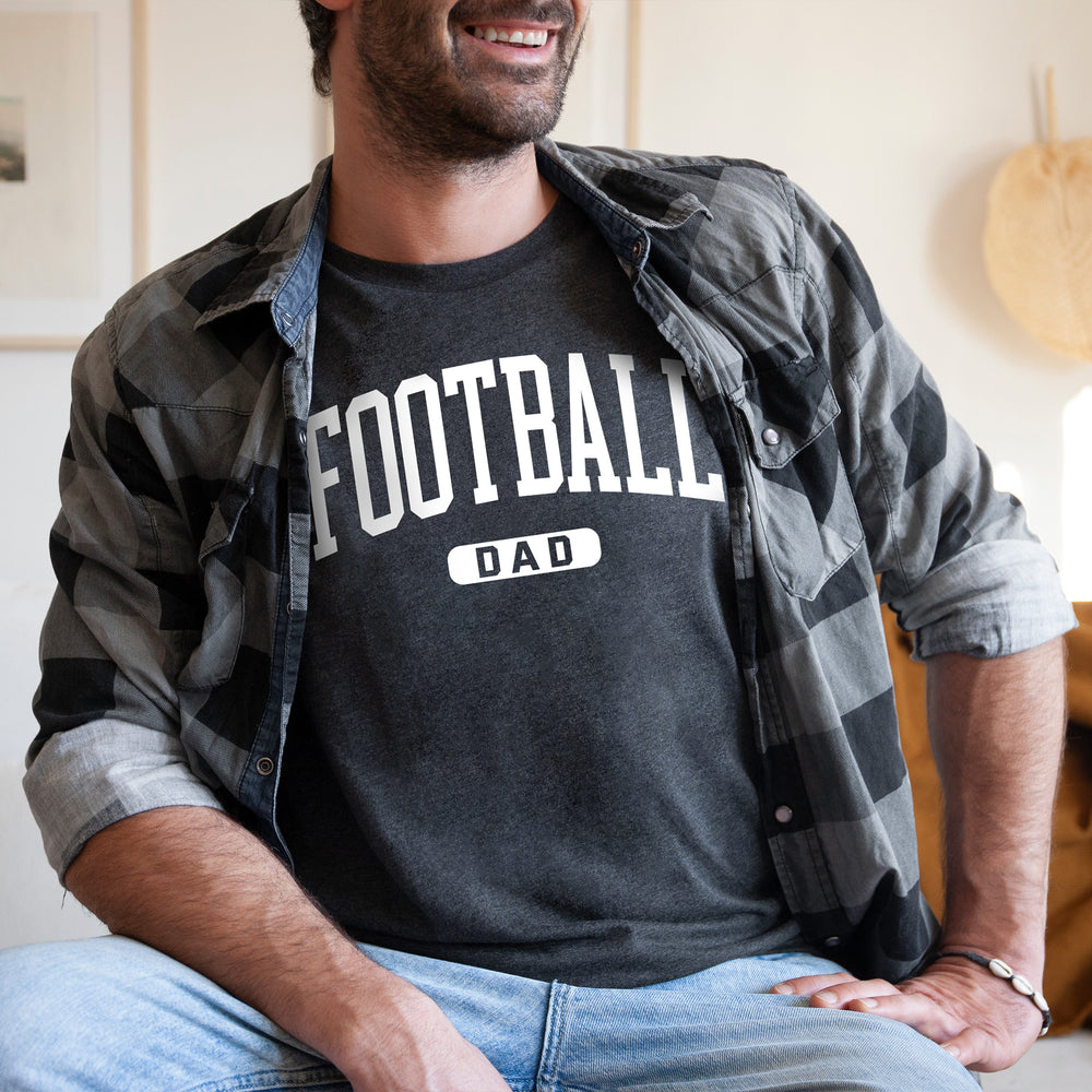 
                  
                    a young man wearing a football dad shirt in dark grey
                  
                