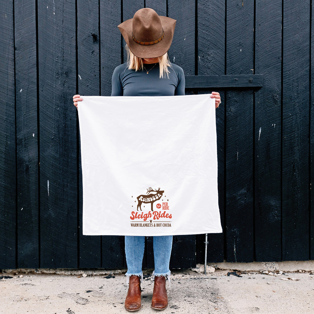 
                  
                    a woman holding an unfolded, reindeer sleigh rides, retro christmas kitchen towel
                  
                
