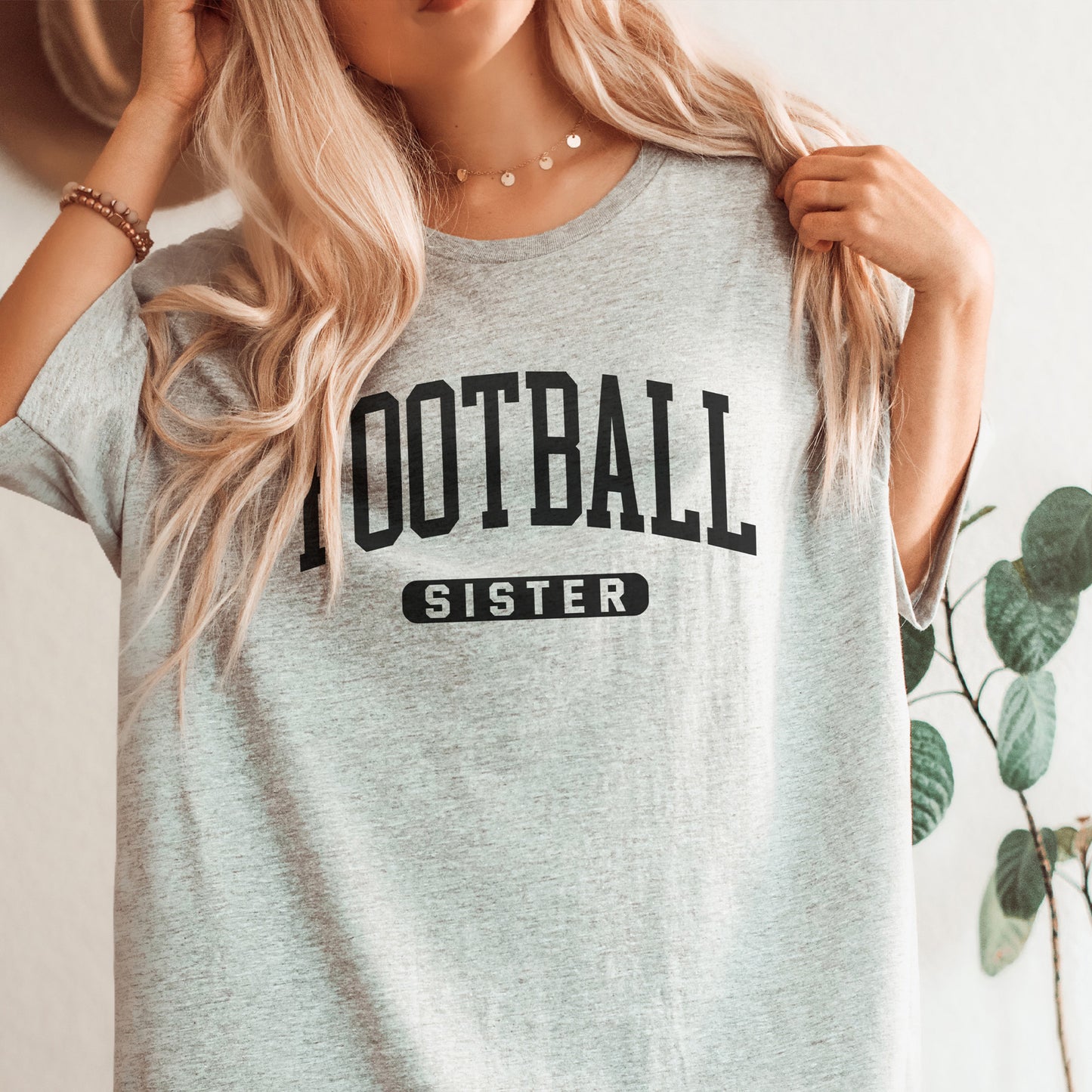 
                  
                    a young woman wearing  a football sister shirt in grey
                  
                