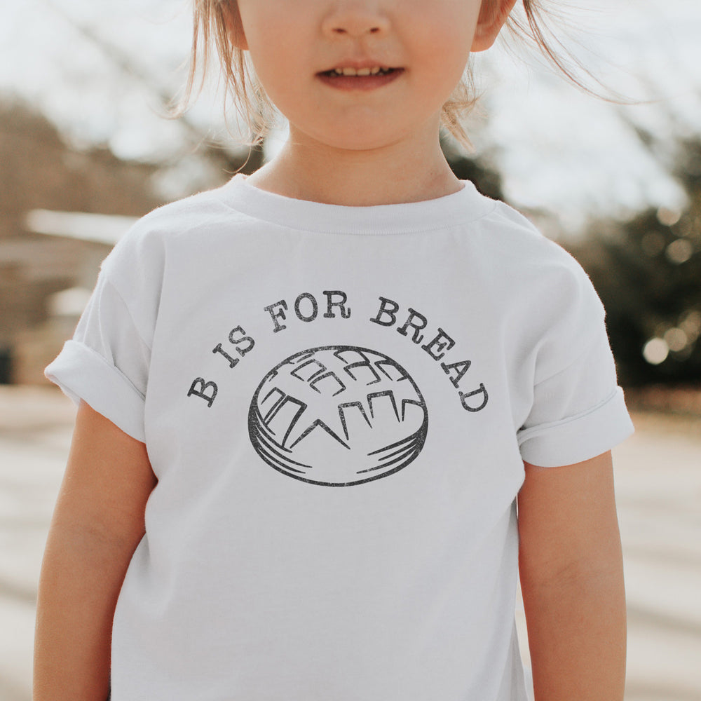 a child wearing a B is for bread kids shirt in white