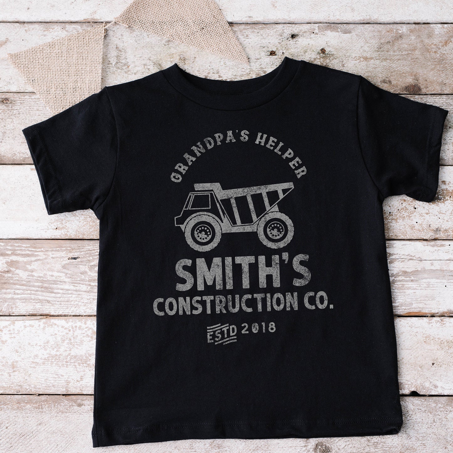 
                  
                    a kid's dump truck construction co. shirt in black
                  
                