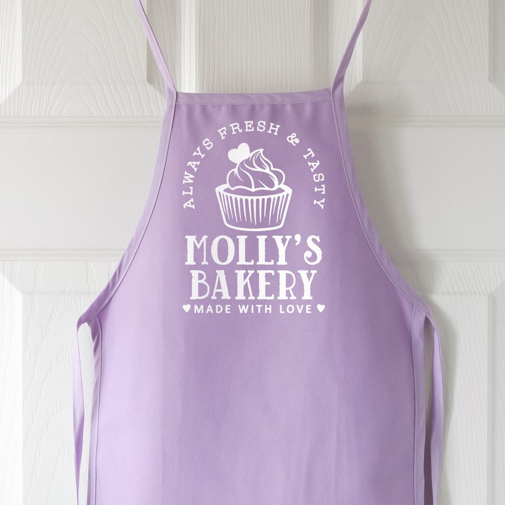 
                  
                    a toddler personalized cupcake baking aprons in purple pastel
                  
                