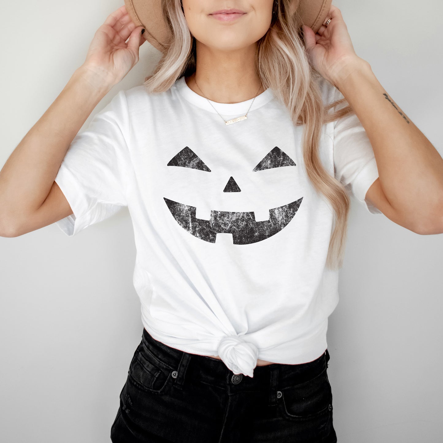 
                  
                    a young woman wearing a Halloween pumpkin face tee in white
                  
                