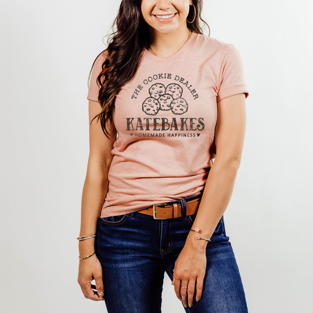 
                  
                    a pretty  young woman wearing a personalized cookie baking shirt in peach
                  
                