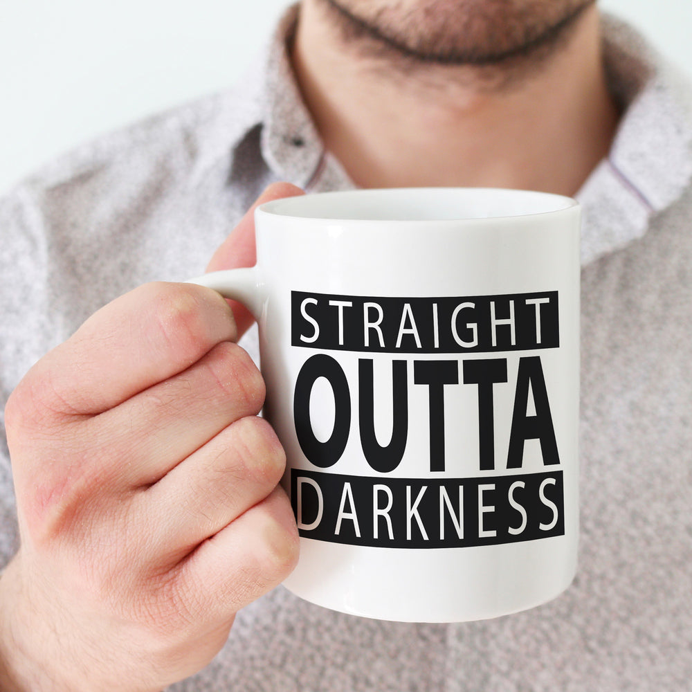 
                  
                    Straight outta darkness svg shown on a white mug, held by a man
                  
                